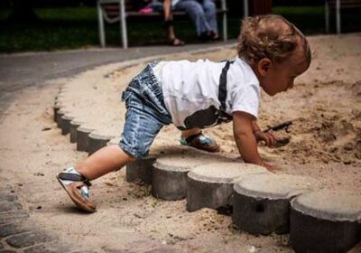 Dziecko idące na czworaka do piaskownicy w butach dla malucha typu barefoot